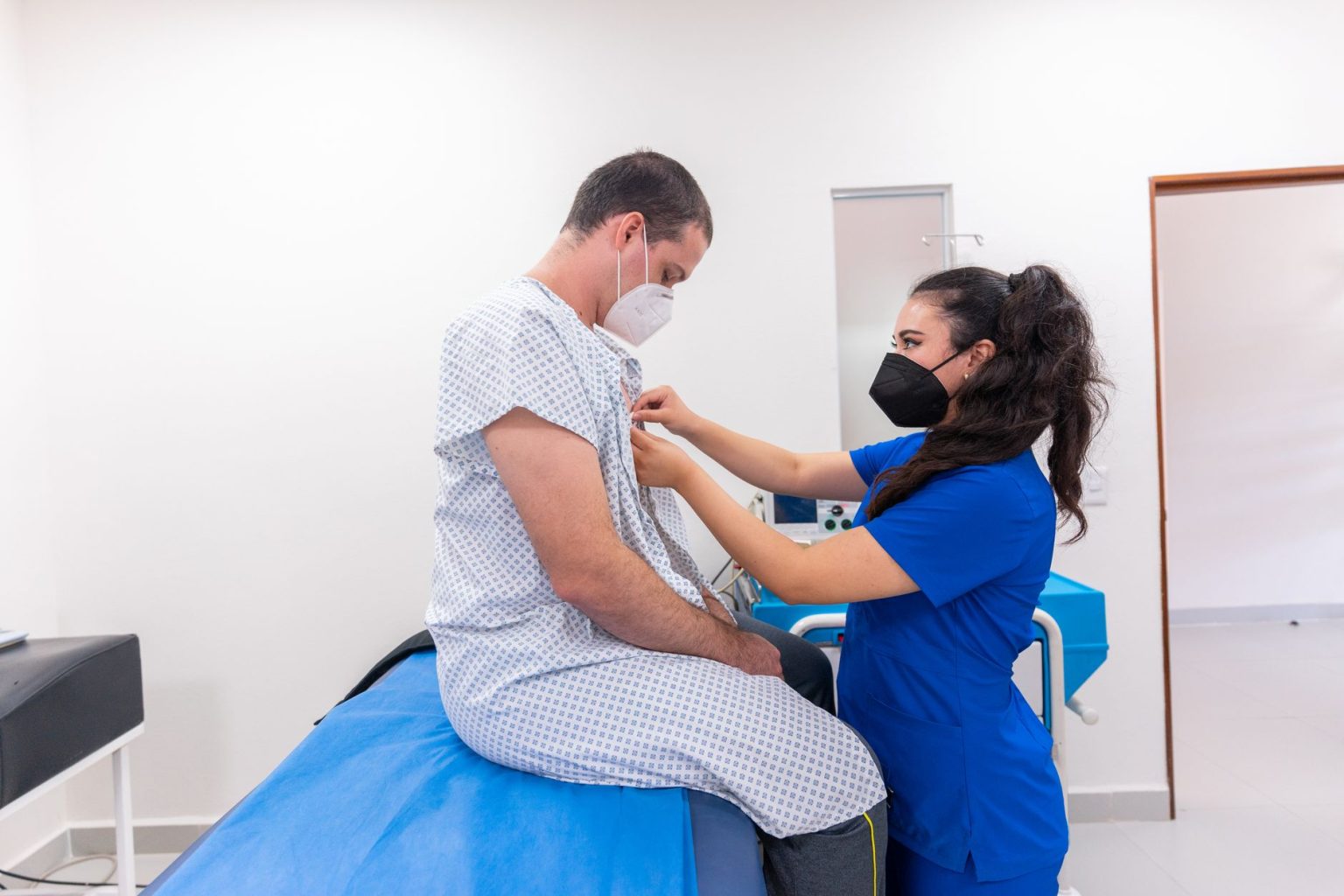 Profissional de enfermagem auxilia paciente durante um exame em ambiente hospitalar.