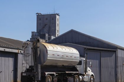 Caminhão semirreboque estacionado junto a um armazém industrial de grãos.