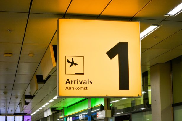 Placa de chegadas com símbolo de avião em um terminal de aeroporto.