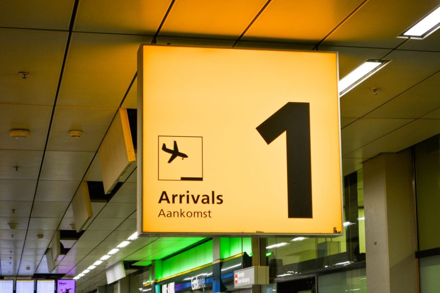 Placa de chegadas com símbolo de avião em um terminal de aeroporto.