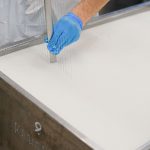 Trabalhador utiliza uma ferramenta durante a produção de queijos em uma unidade de laticínios