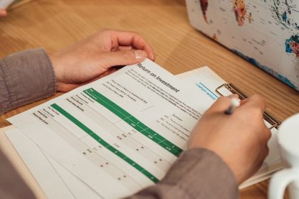 Pessoa analisando um relatório de retorno sobre investimento com uma caneta sobre a mesa.