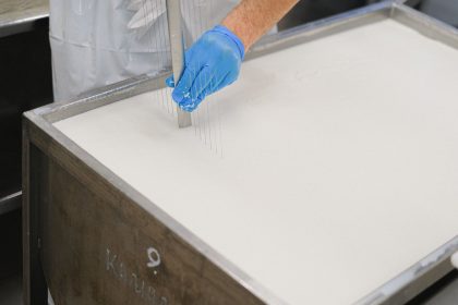 Trabalhador utiliza uma ferramenta durante a produção de queijos em uma unidade de laticínios