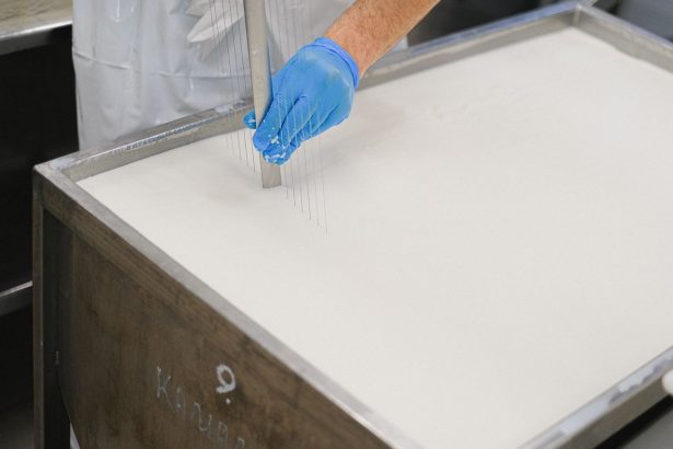 Trabalhador utiliza uma ferramenta durante a produção de queijos em uma unidade de laticínios