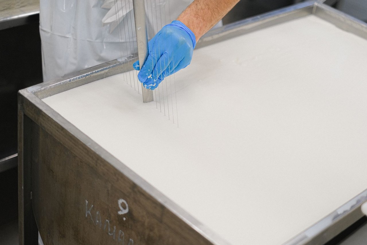 Trabalhador utiliza uma ferramenta durante a produção de queijos em uma unidade de laticínios
