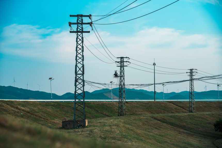 Linhas de transmissão de alta tensão próximas a aerogeradores em uma paisagem rural.
